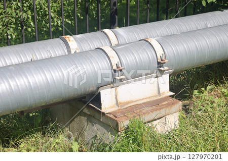 Two pipes of the heating system are fastened with metal clamps to a concrete support. 127970201