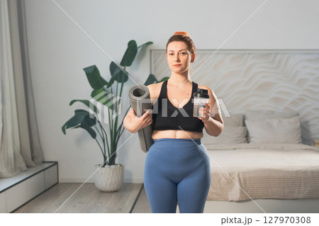 Yoga fitness sport workout training. Woman hold yoga mat bottle water ready for practicing yoga at home. Plus size female doing sports indoor. Girl in sportswear have training workout for weight loss 127970308