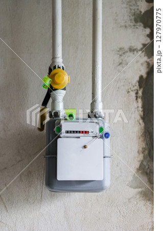 Vertical photo of gas meter and pipes, on concrete wall in a house under renewal. Indoor gas meter used for measuring natural gas consumption in residential buildings, houses. Energy crisis in Europe 127970775