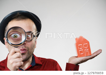 Man magnifying red house Man magnifying red house 127970859