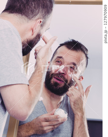 Man applying moisturizer cream in bathroom 127970909
