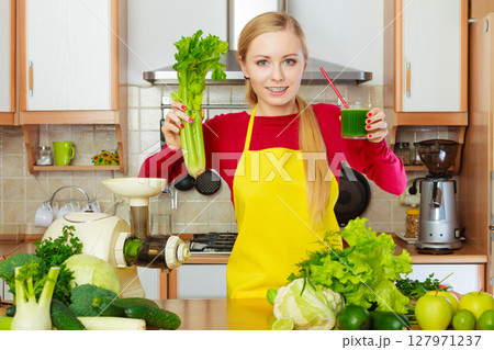 Woman in kitchen holding vegetable smoothie juice Woman in kitchen holding vegetable smoothie juice 127971237