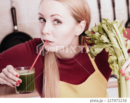 Woman in kitchen holding vegetable smoothie juice 127971238