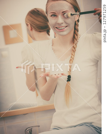 Woman with grey clay mud mask on her face 127971259