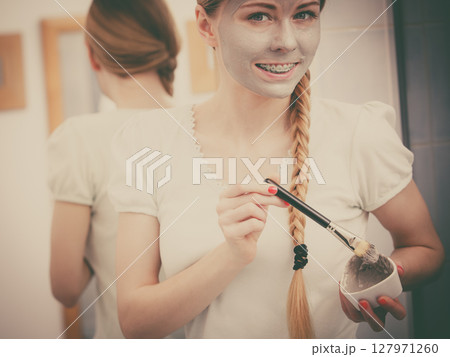 Woman with grey clay mud mask on her face Woman with grey clay mud mask on her face 127971260