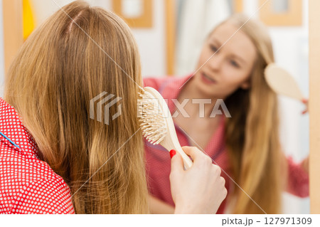 Woman brushing her long hair in bathroom 127971309