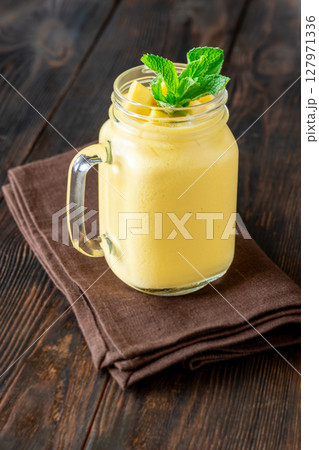 Chilled mango lassi in mason jar topped with mint and mango cubes Chilled mango lassi in mason jar topped with mint and mango cubes 127971336
