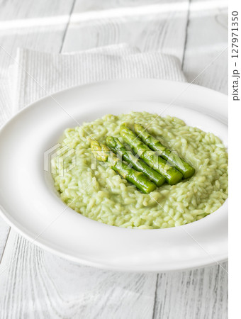 Asparagus risotto served in white plate with whole spears on top 127971350