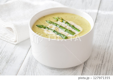 Creamy asparagus soup in white bowl with swirl and toasted ciabatta 127971355