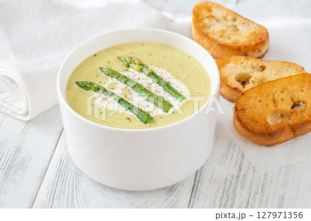 Creamy asparagus soup in white bowl with swirl and toasted ciabatta Creamy asparagus soup in white bowl with swirl and toasted ciabatta 127971356