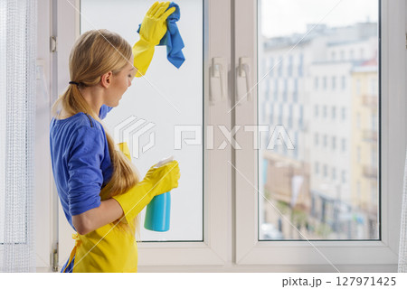 Woman cleaning window at home Woman cleaning window at home 127971425