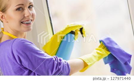 Girl cleaning window at home 127971440