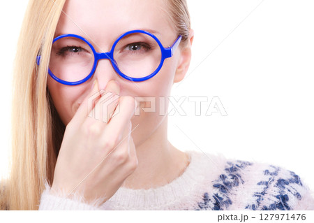 Nerdy woman holding nose smelling bad scent 127971476