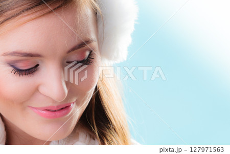 Happy woman in white earmuffs on blue 127971563