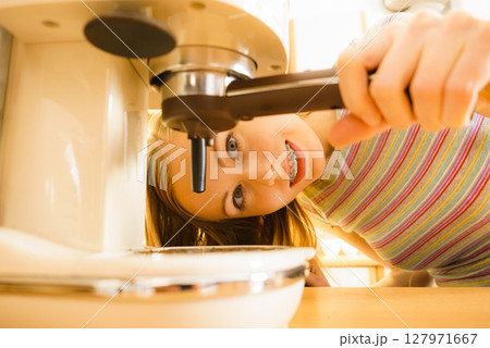 Woman in kitchen making coffee from machine Woman in kitchen making coffee from machine 127971667
