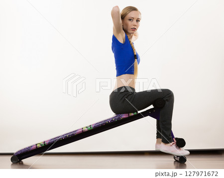 Woman training on bench for sit ups 127971672