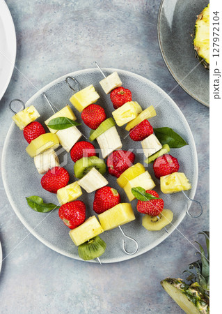 Plate of mixed fruits on skewers. Plate of mixed fruits on skewers. 127972104