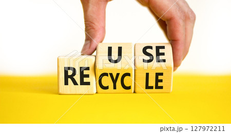 Reuse or recycle symbol. Concept words Reuse Recycle on wooden block. Beautiful yellow table white background. Businessman hand. Business reuse or recycle concept. Copy space. 127972211