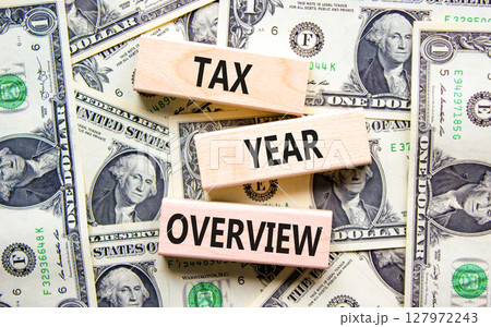 Tax year overview symbol. Concept words Tax year overview on beautiful wooden blocks. Dollar bills. Beautiful background from dollar bills. Business tax year overview concept. Copy space. Tax year overview symbol. Concept words Tax year overview on beautiful wooden blocks. Dollar bills. Beautiful background from dollar bills. Business tax year overview concept. Copy space. 127972243