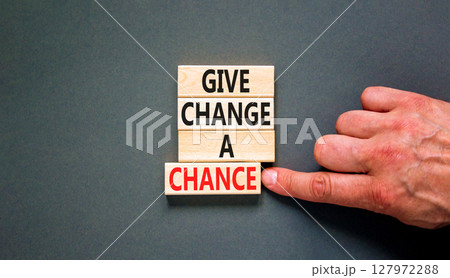 Give change a chance symbol. Concept words phrase Give change a chance on beautiful wooden blocks. Beautiful grey paper background. Businessman's hand. Business Give change a chance concept Copy space 127972288