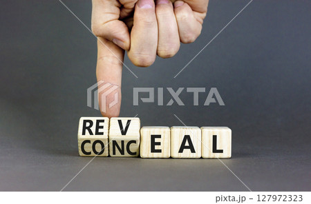 Reveal or conceal symbol. Businessman turns wooden cubes and changes word Conceal to Reveal. Beautiful grey table grey background, copy space. Business reveal or conceal concept. Reveal or conceal symbol. Businessman turns wooden cubes and changes word Conceal to Reveal. Beautiful grey table grey background, copy space. Business reveal or conceal concept. 127972323