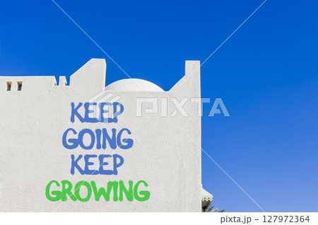 Keep going and growing symbol. Concept words phrase Keep going keep growing on beautiful white wall. Beautiful white wall and blue sky background. Business Keep going and growing concept. Copy space. 127972364