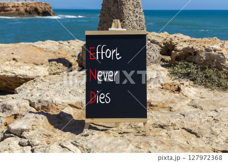 END effort never dies symbol. Concept words END effort never dies on beautiful yellow blackboard. Beautiful stone blue sky sea background. Business END effort never dies concept. Copy space. 127972368
