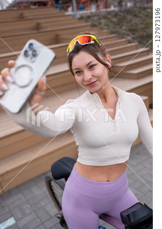 Stylish and Sporty Young Woman is Joyfully Taking a Fun Selfie While Riding Her Bicycle Stylish and Sporty Young Woman is Joyfully Taking a Fun Selfie While Riding Her Bicycle 127973196