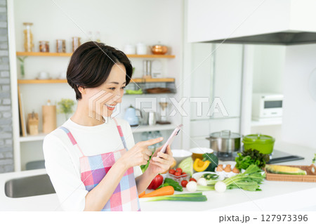 キッチンでスマホを使うミドルの主婦 127973396