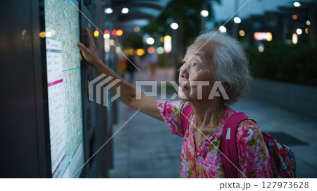 Elderly woman in floral shirt using digital map at night, looking focused Elderly woman in floral shirt using digital map at night, looking focused 127973628
