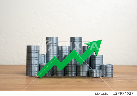Stacks of money coins and a green arrow pointing up. Increasing income and wealth. Growth of the money supply. Increasing the economy. Wealth growth, capital accumulation, or a booming economy. 127974027