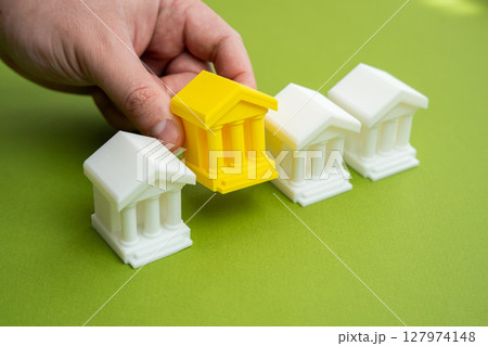 Hand choosing yellow bank building. Choosing the best banking for business and investment. Services, trust, capital strategy. Creditworthiness, economic decisions. Hand choosing yellow bank building. Choosing the best banking for business and investment. Services, trust, capital strategy. Creditworthiness, economic decisions. 127974148