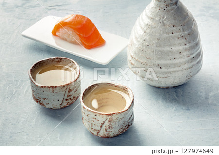 Sake in a pitcher and ochoko, traditional cup, with salmon nigiri 127974649