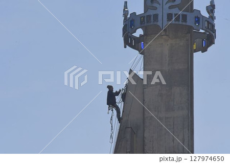 A craftsman repairs the tower of a modern church. A tinsmith repairs the tower of a modern building. The concept of working at heights and work safety 127974650