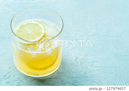 A glass of lemonade, a mocktail with lemon juice, on a blue background A glass of lemonade, a mocktail with lemon juice, on a blue background 127974657