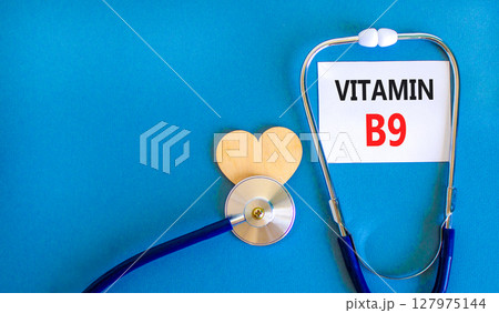 Vitamin B9 folic acid symbol. Concept words Vitamin B9 on beautiful white card. Wooden heart and stethoscope. Beautiful blue background. Medical healthy lifestyle Vitamin B9 concept. Vitamin B9 folic acid symbol. Concept words Vitamin B9 on beautiful white card. Wooden heart and stethoscope. Beautiful blue background. Medical healthy lifestyle Vitamin B9 concept. 127975144