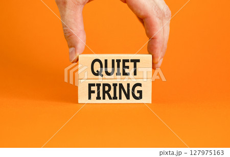 Quiet firing symbol. Concept words Quiet firing on wooden blocks. Beautiful orange table orange background. Businessman hand. Business and quiet firing concept. Copy space. 127975163