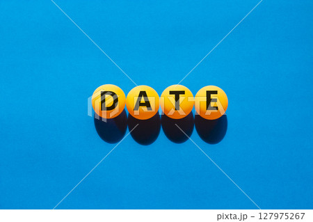 Date symbol. Concept word Date on beautiful yellow ping pong balls. Beautiful blue table blue background. Business and date concept. Copy space. 127975267