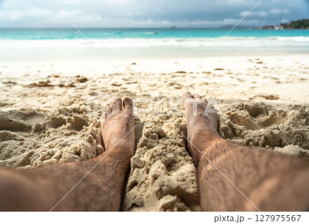 Bare feet resting in warm sand on tropical beach, symbolizing summer relaxation, freedom 127975567