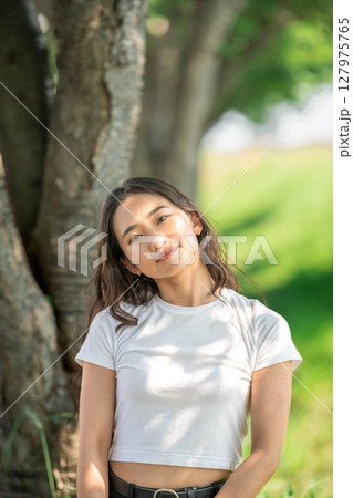 木漏れ日の中でリラックスする若い女性のポートレート 127975765