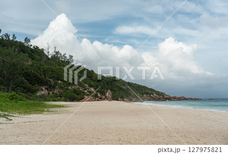 Cumulus rain clouds build over an empty beach on La Digue island during the tropical off-season Cumulus rain clouds build over an empty beach on La Digue island during the tropical off-season 127975821