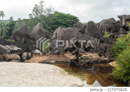 Tropical beach meets a shallow swamp surrounded by granite boulders and vegetation Tropical beach meets a shallow swamp surrounded by granite boulders and vegetation 127975828
