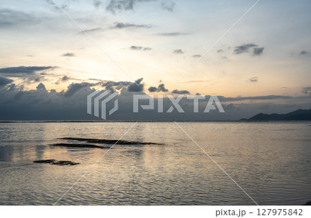 Cloud layers above calm sea reflect soft light at dusk near La Digue island, Seychelles Cloud layers above calm sea reflect soft light at dusk near La Digue island, Seychelles 127975842