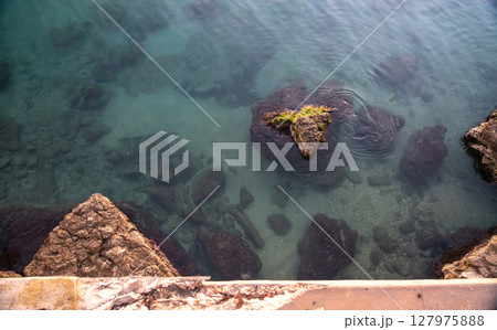 Clear ocean water reveals submerged rocks near an old stone fort wall Clear ocean water reveals submerged rocks near an old stone fort wall 127975888