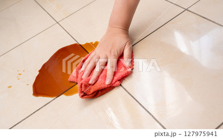 Spilled coffee, coffe puddle stain on tiled floor, messy leak with fallen cup, brown drink spillage 127975941