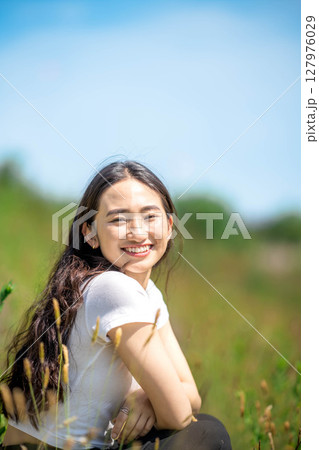 青空のもとでリラックスする若い女性 127976029