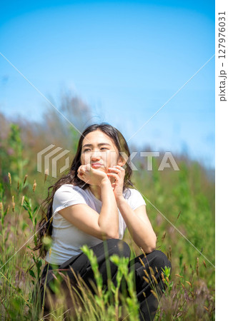 青空のもとでリラックスする若い女性 127976031