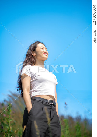 青空のもとでリラックスする若い女性 127976034