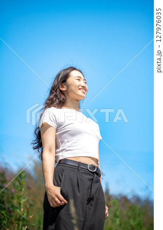 青空のもとでリラックスする若い女性 127976035