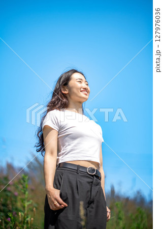 青空のもとでリラックスする若い女性 127976036